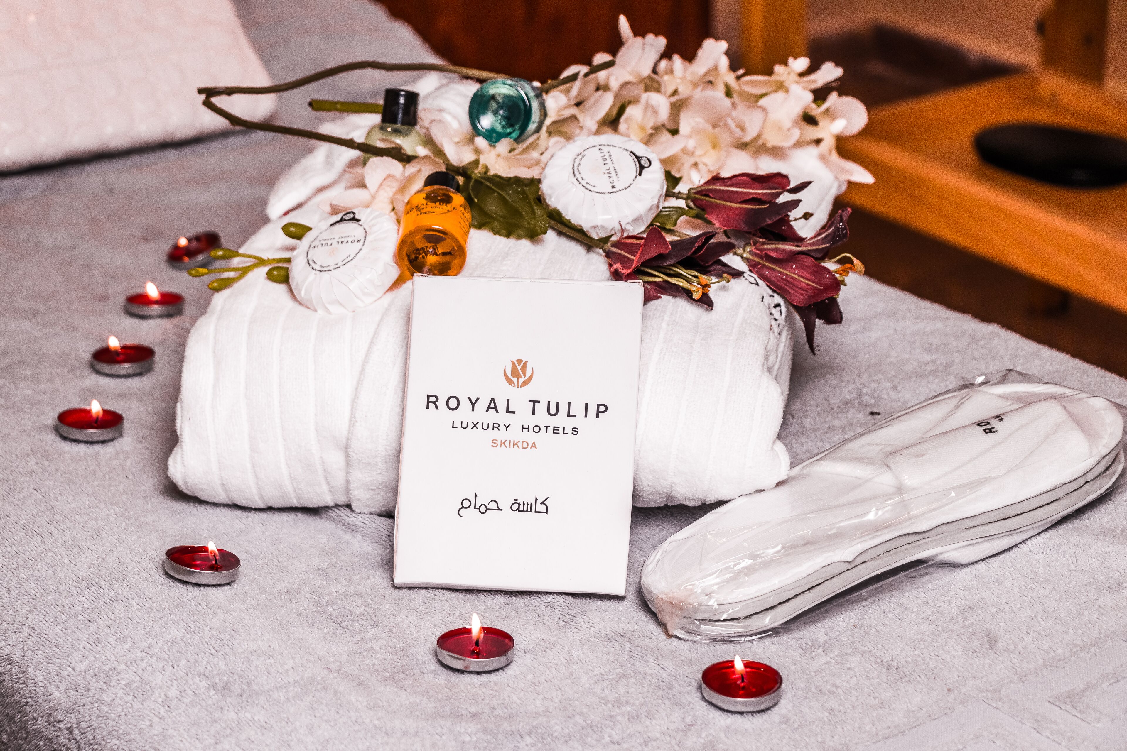 A luxurious hotel setting with a white towel, a card, and candles on a textured surface.