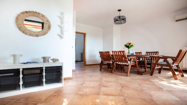 Uma área de refeições com um armário branco, cadeiras de madeira e uma mesa.