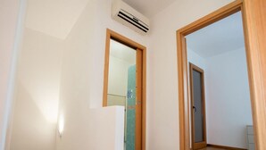 Um corredor com moldura de porta de madeira, um espelho e um aparelho de ar condicionado na parede.