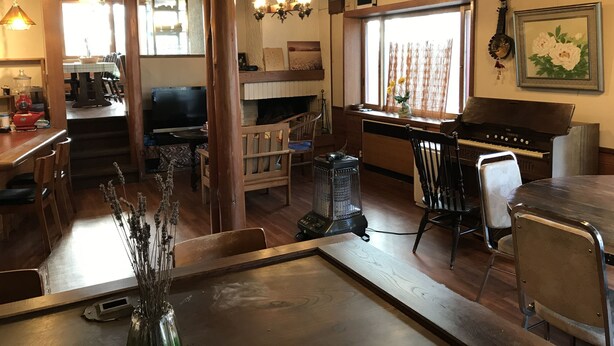 A cozy interior with a dining area, piano, and a kitchen visible through an open door. - New togakushi schiheil (Nagano)