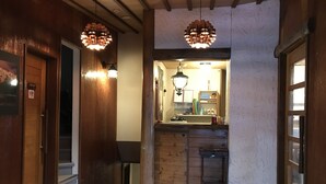 A wooden interior with a wooden floor, a small kitchenette with a sink and cabinets, and two pendant lights. - New togakushi schiheil (Nagano)