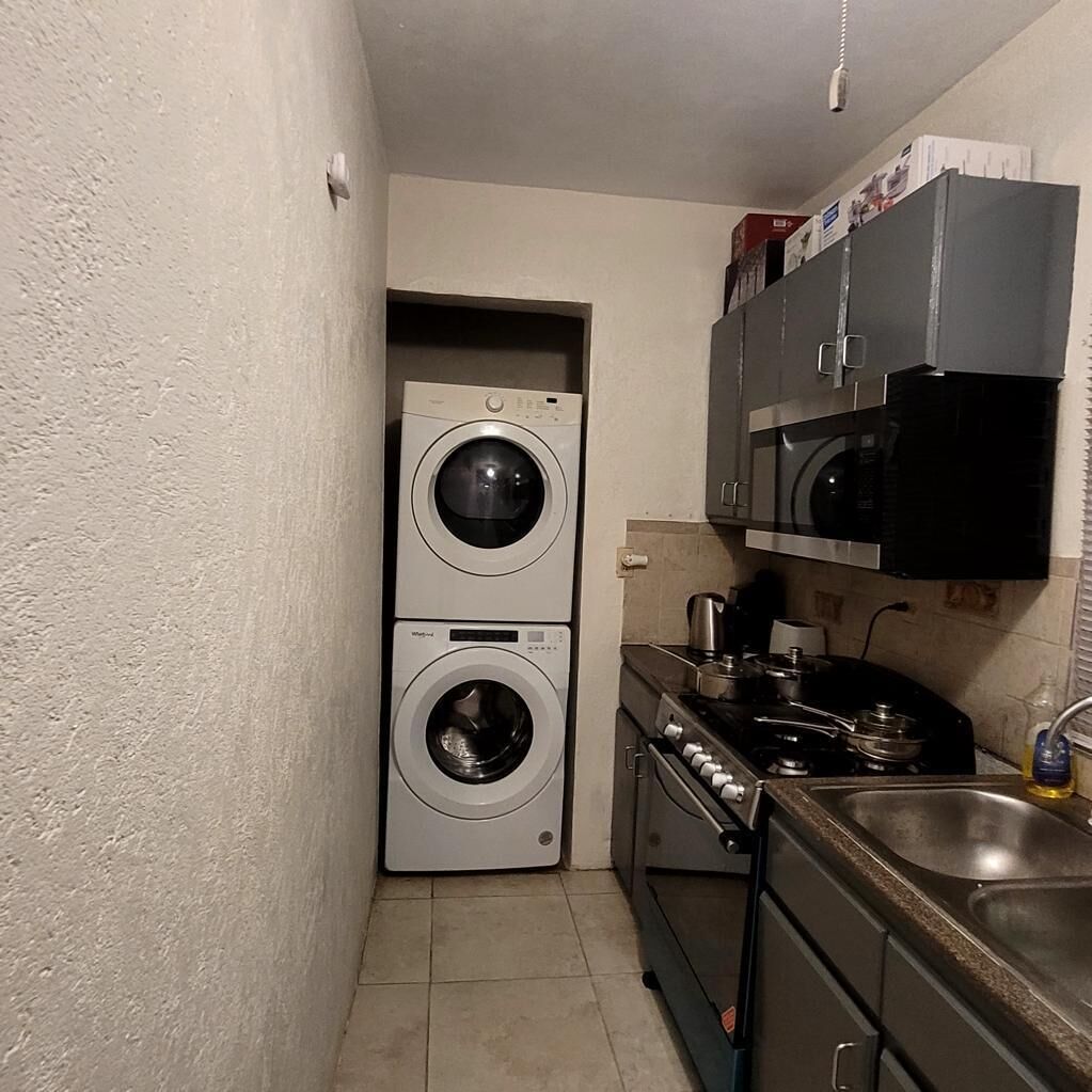 Una cocina compacta equipada con lavadora, microondas y cocina.