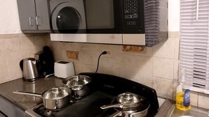 Eine Küche mit Mikrowelle, Herd, Töpfen und Spüle.