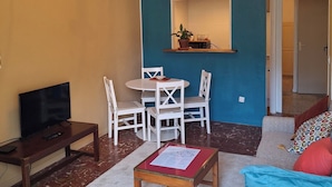 Un soggiorno con TV, tavolino in legno, parete decorata in blu, lampadario e divano con cuscini.