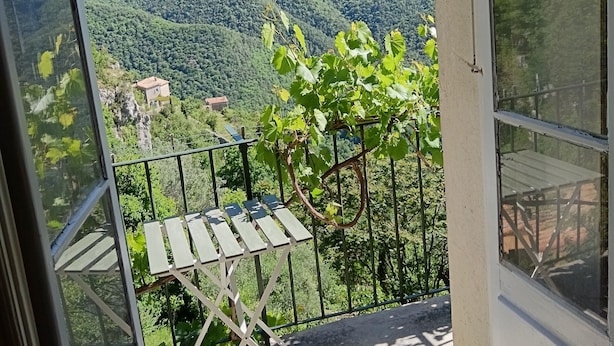 Un balcone con tavolo e sedie, affacciato su un paesaggio montuoso.