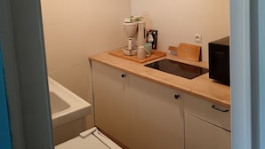 Una piccola cucina accessoriata con macchina del caffè, forno a microonde e lavandino.