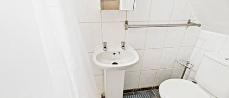 A small, white bathroom with a sink, toilet, and a mirror above the sink.