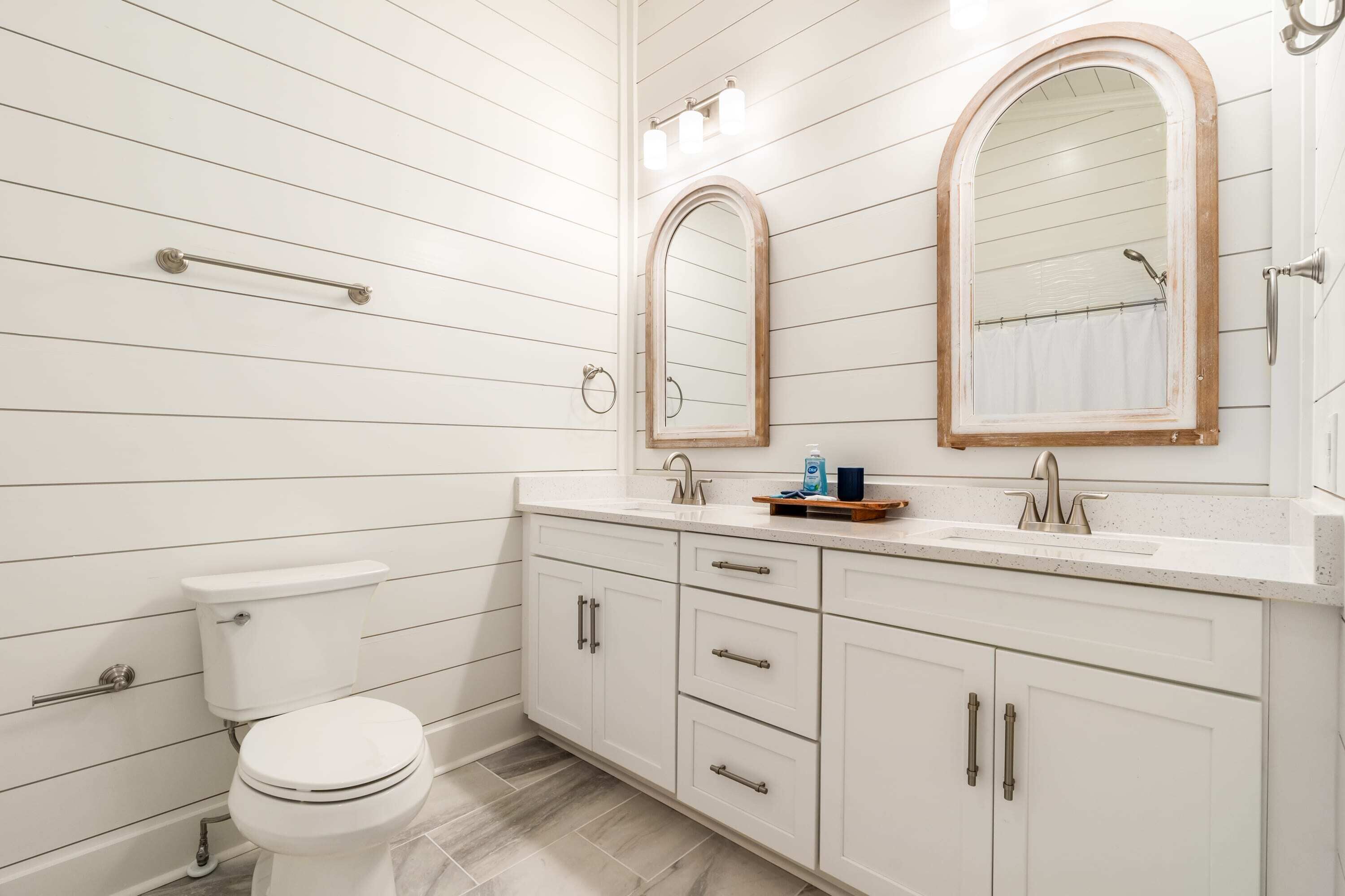 A bathroom with a toilet, a sink with a mirror, and a shower.