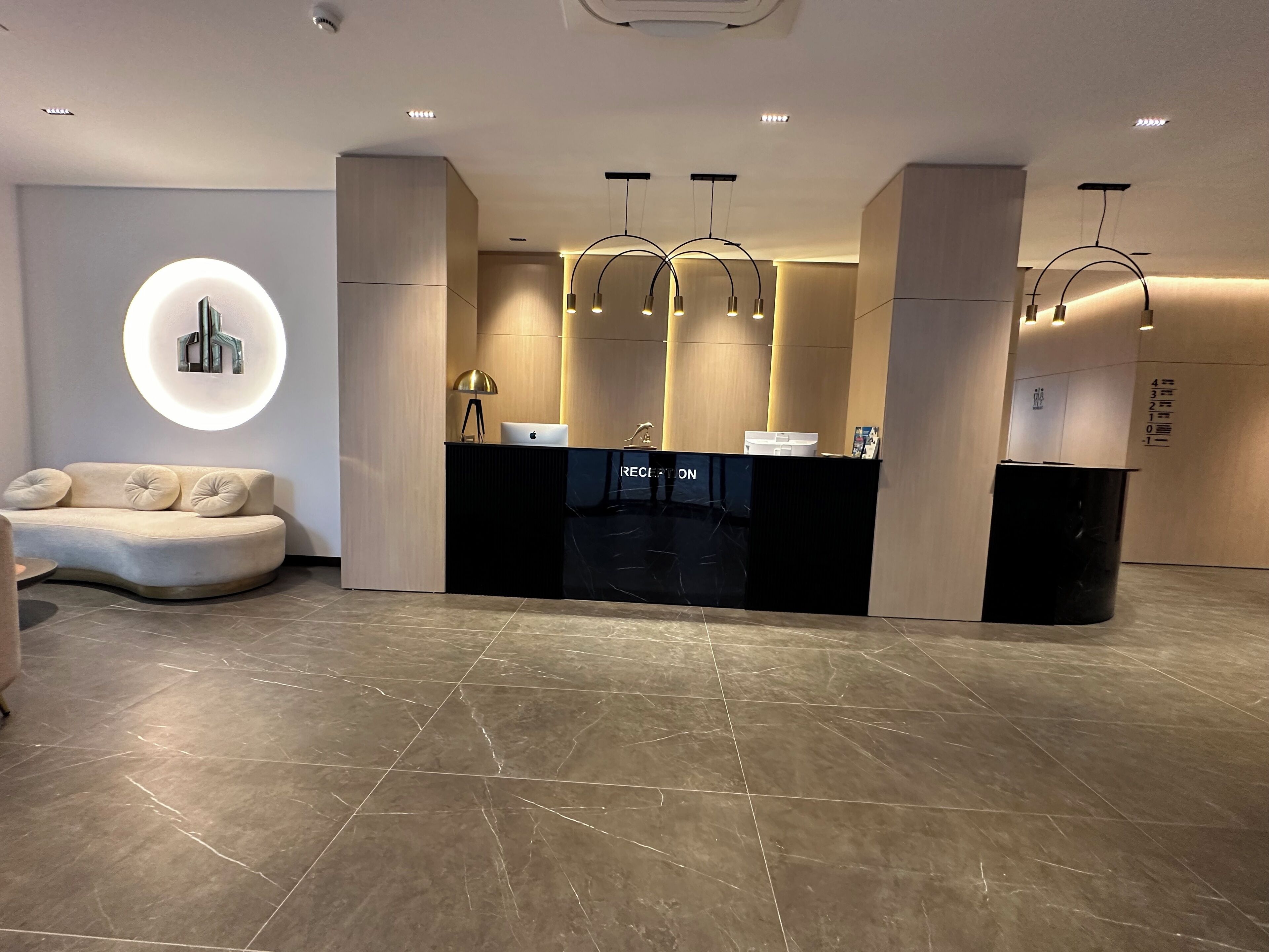 A reception area with a black reception desk, a sofa, and a circular light fixture on the wall.