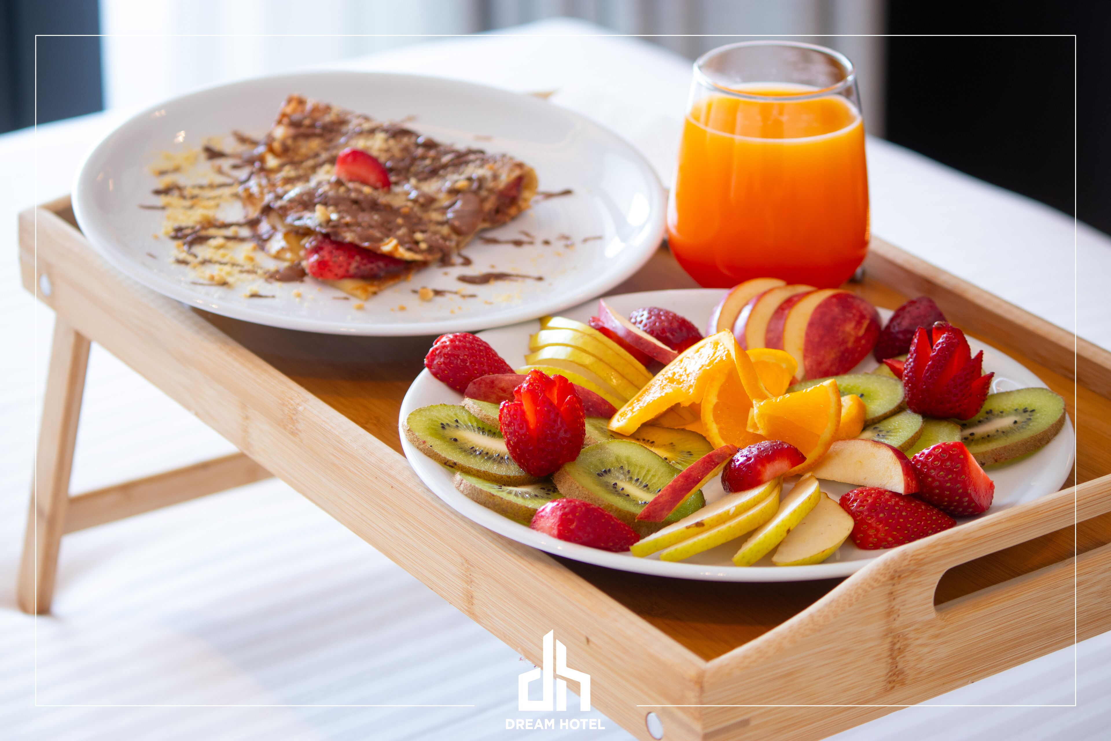 A breakfast tray with a plate of fruit and a glass of orange juice.