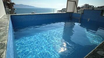 Une piscine d’un bleu éclatant, avec une vue sur la mer et les montagnes en arrière-plan.