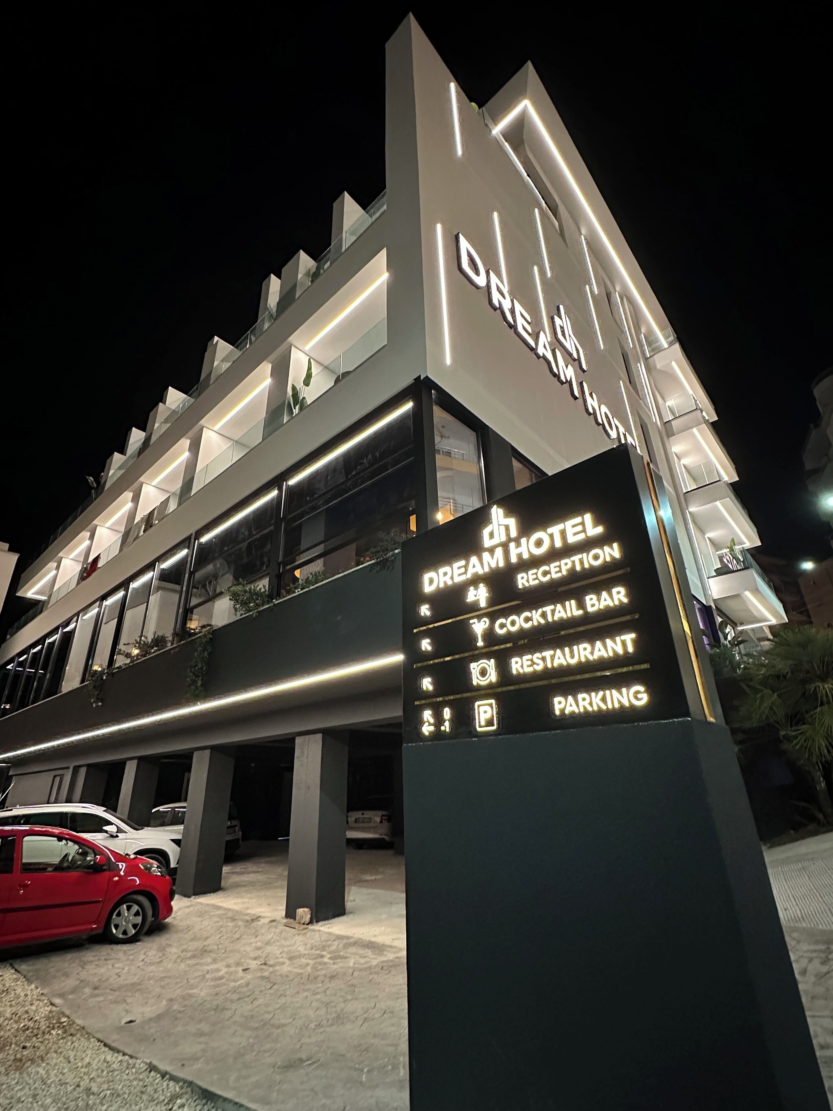 Un hotel moderno con un cartel que indica recepción, bar de cócteles, restaurante y aparcamiento.