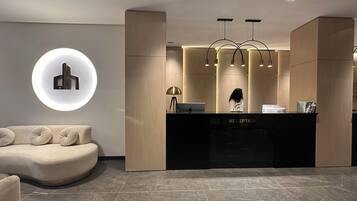 A modern reception area with a curved sofa, a reception desk labeled "RECEPTION," and a circular light fixture on the wall.