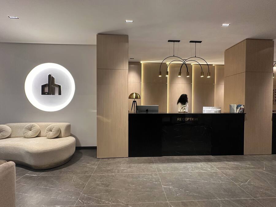 A modern reception area with a curved sofa, a reception desk labeled "RECEPTION," and a circular light fixture on the wall.