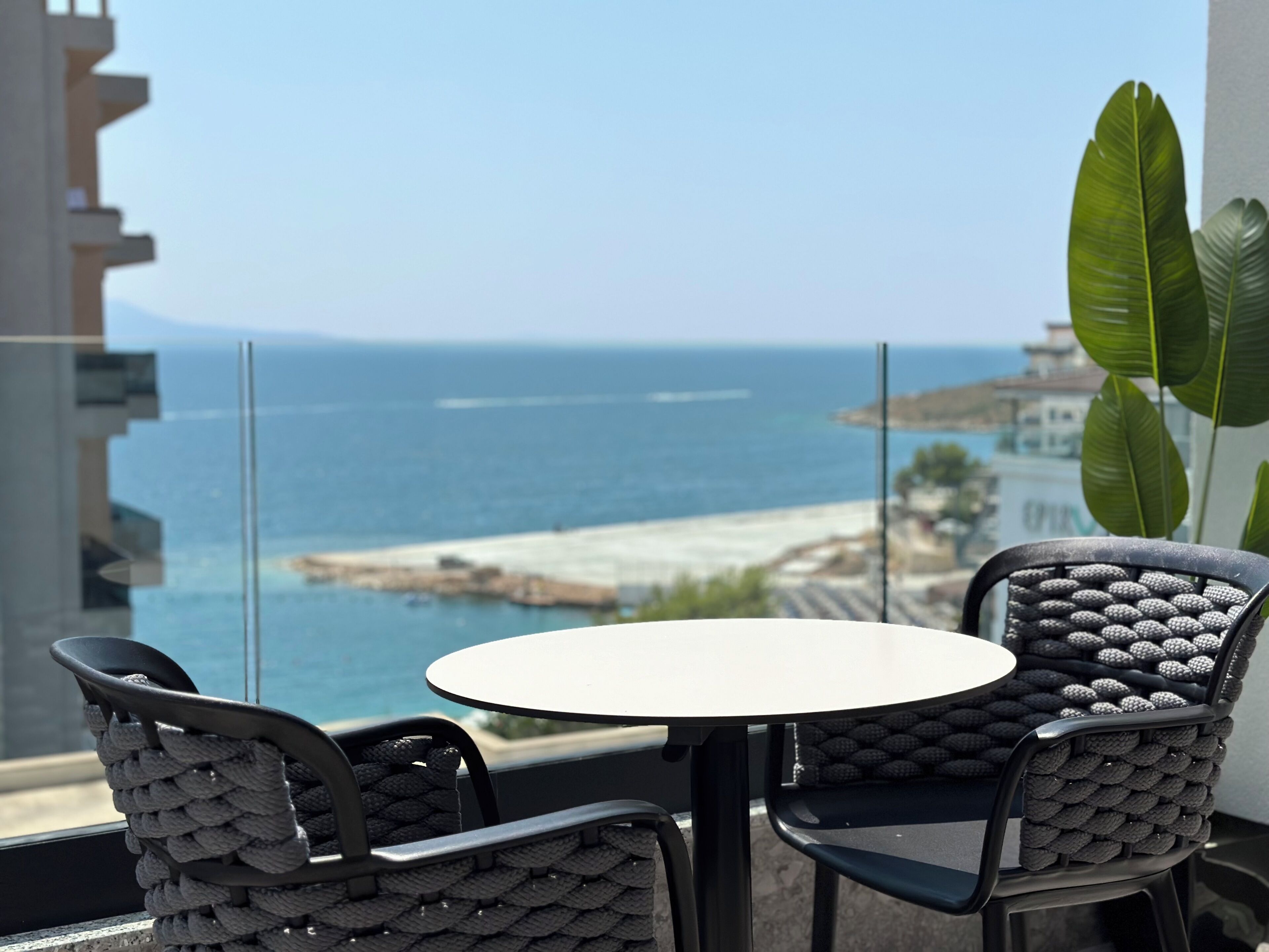 Un balcón con una mesa redonda y dos sillas, con vistas a la costa, al mar y a un litoral rocoso.