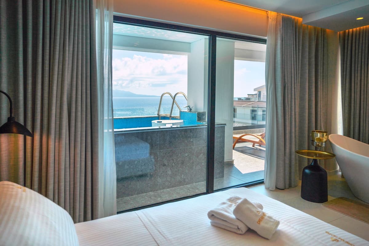 Ein Hotelzimmer mit Bett, Badezimmer mit Badewanne, Waschbecken und Meerblick.