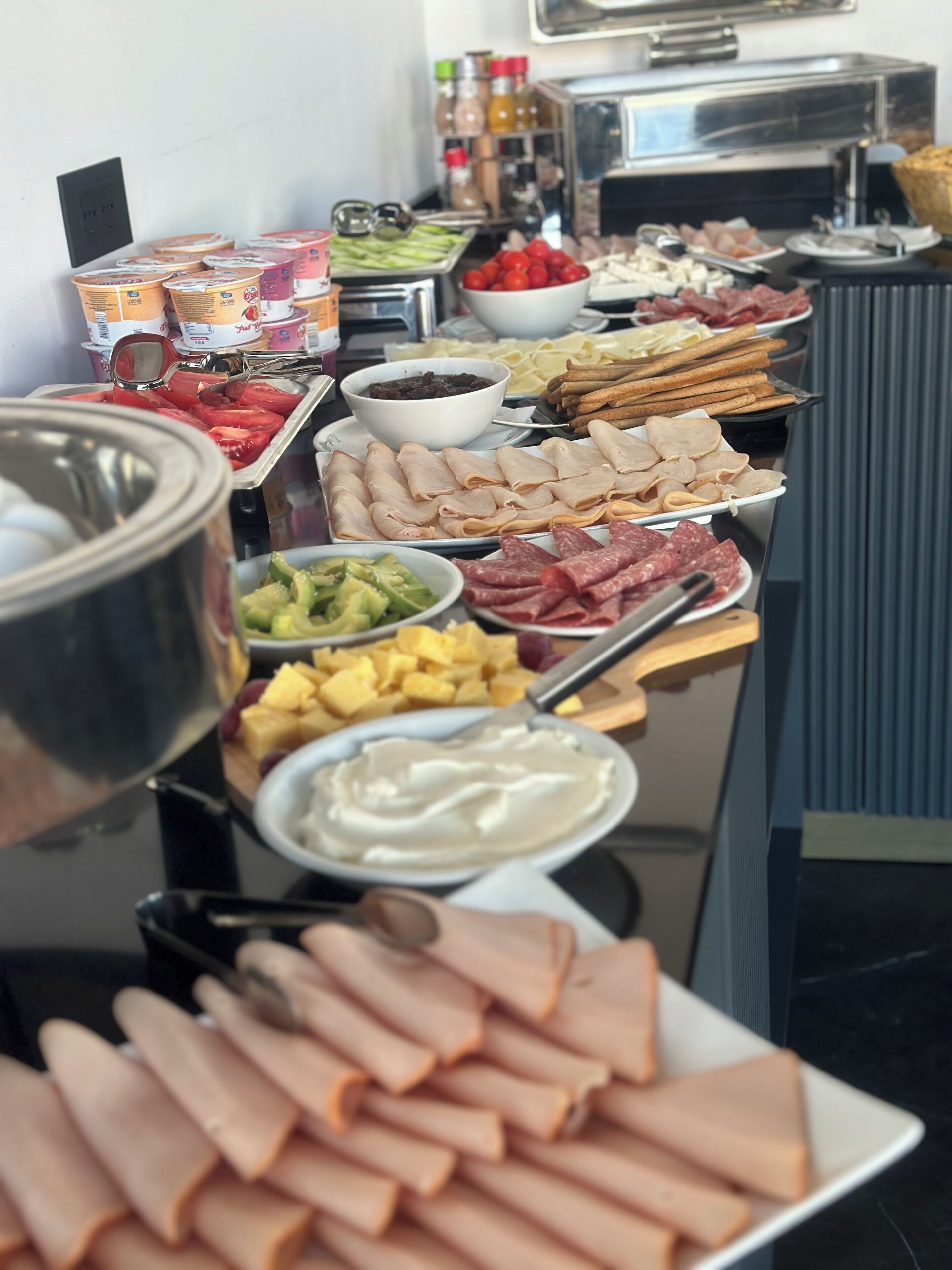 A buffet with various food items including meats, cheeses, and fruits.