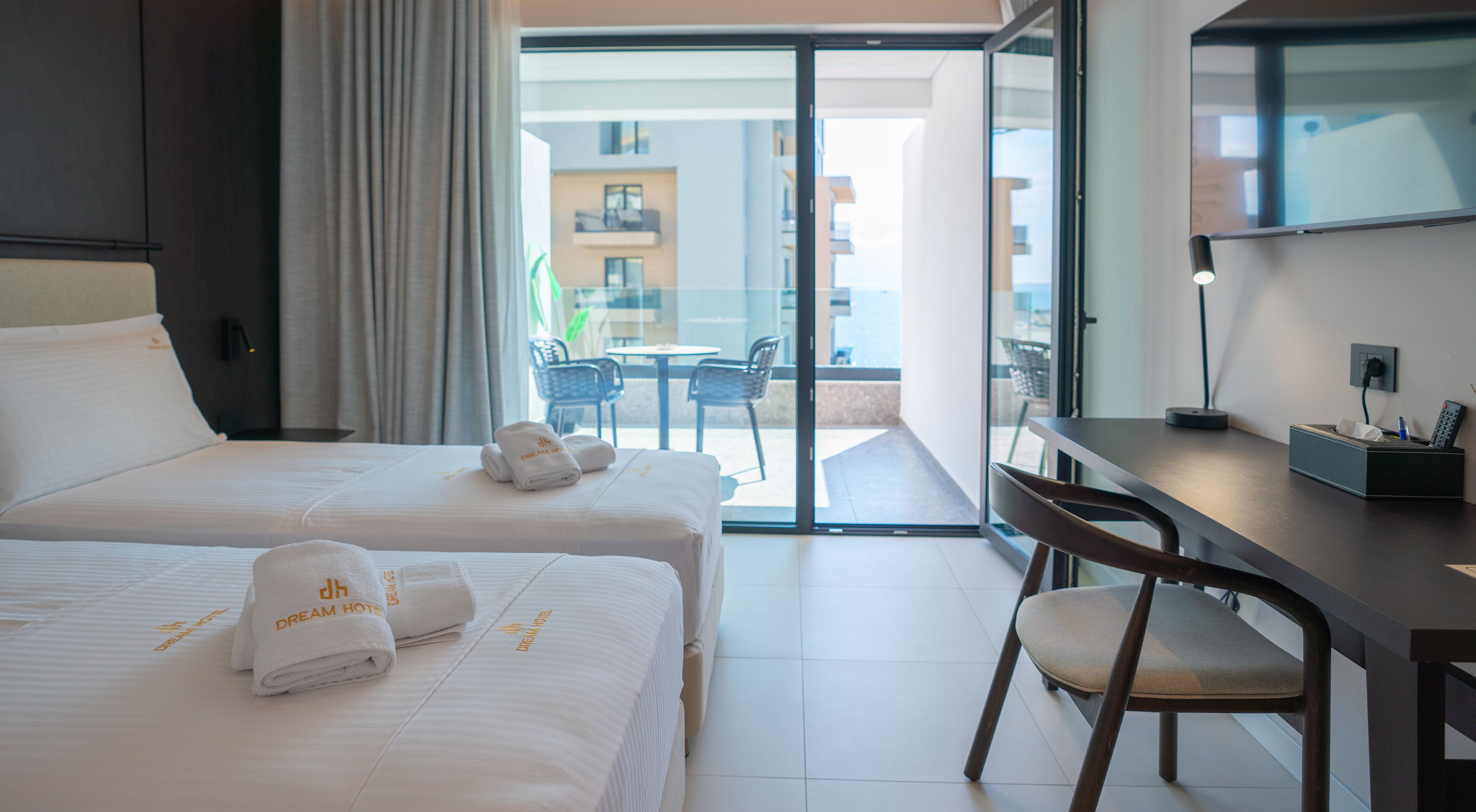 Habitación de hotel con dos camas, un escritorio, una silla y vistas al área exterior.