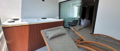 Une salle de bain moderne avec une baignoire en bois, une cabine de douche en verre et un coin salon comprenant une chaise et une petite table.
