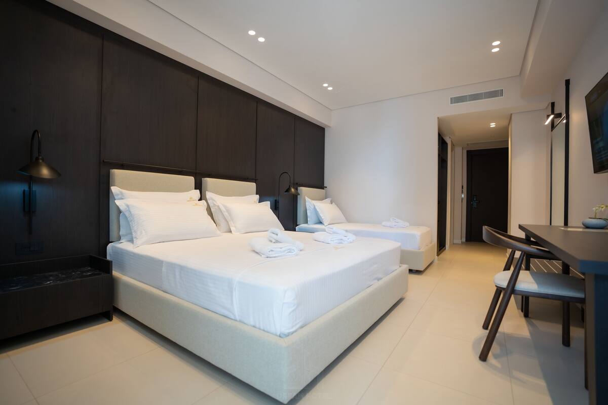 Ein modernes Hotelzimmer mit einem großen Bett, Nachttischen, einem Schreibtisch und einem Sessel.