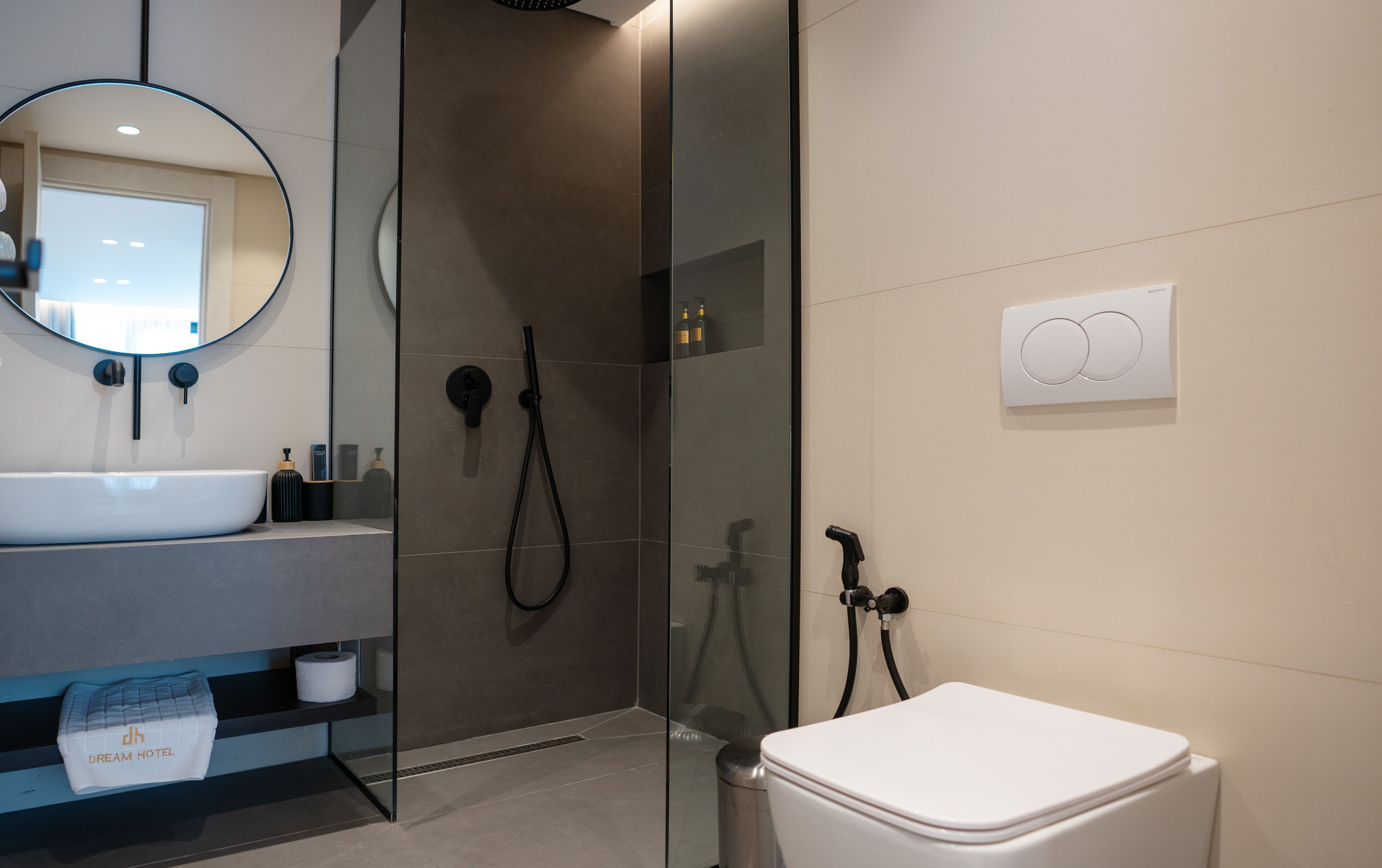 A modern bathroom with a white sink, a glass-enclosed shower, and a toilet.
