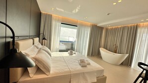 A modern hotel room with a large bed, a bathtub, and a view of the sea. - DREAM HOTEL SARANDA (Sarandë)