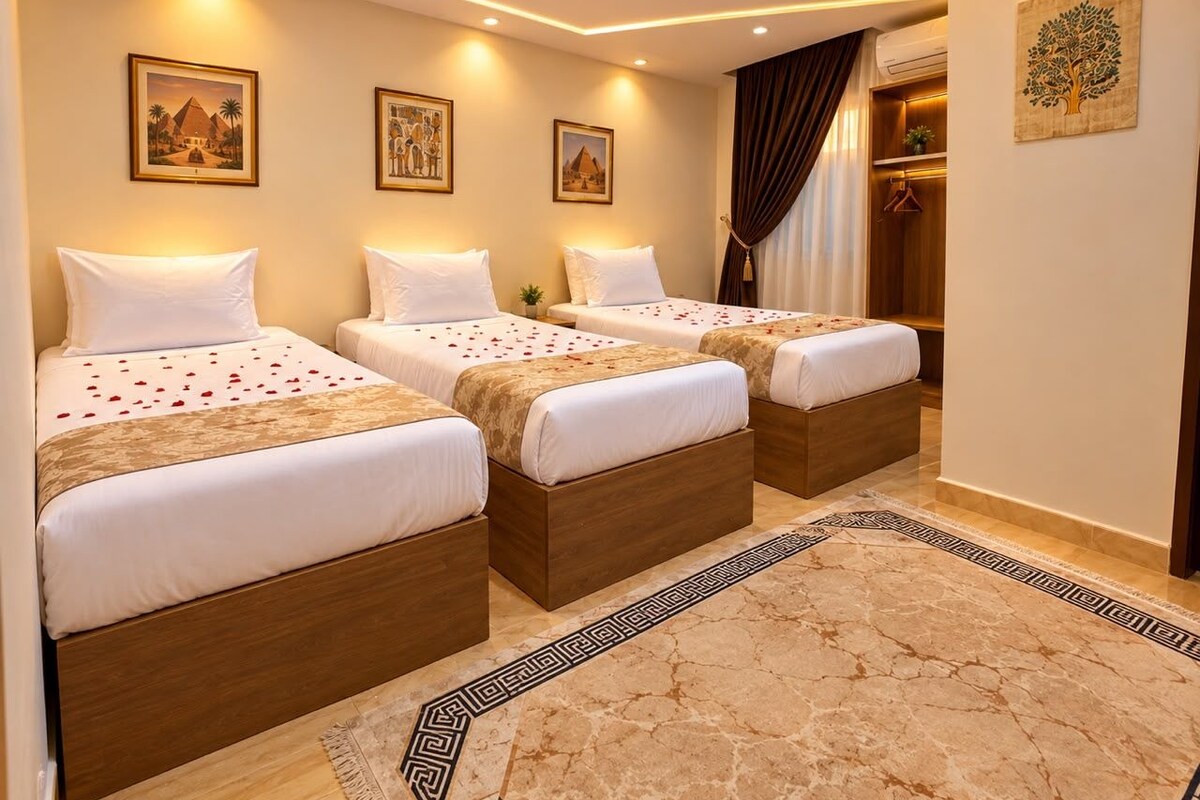 Habitación de hotel con tres camas, piso de mármol y obras de arte en las paredes.