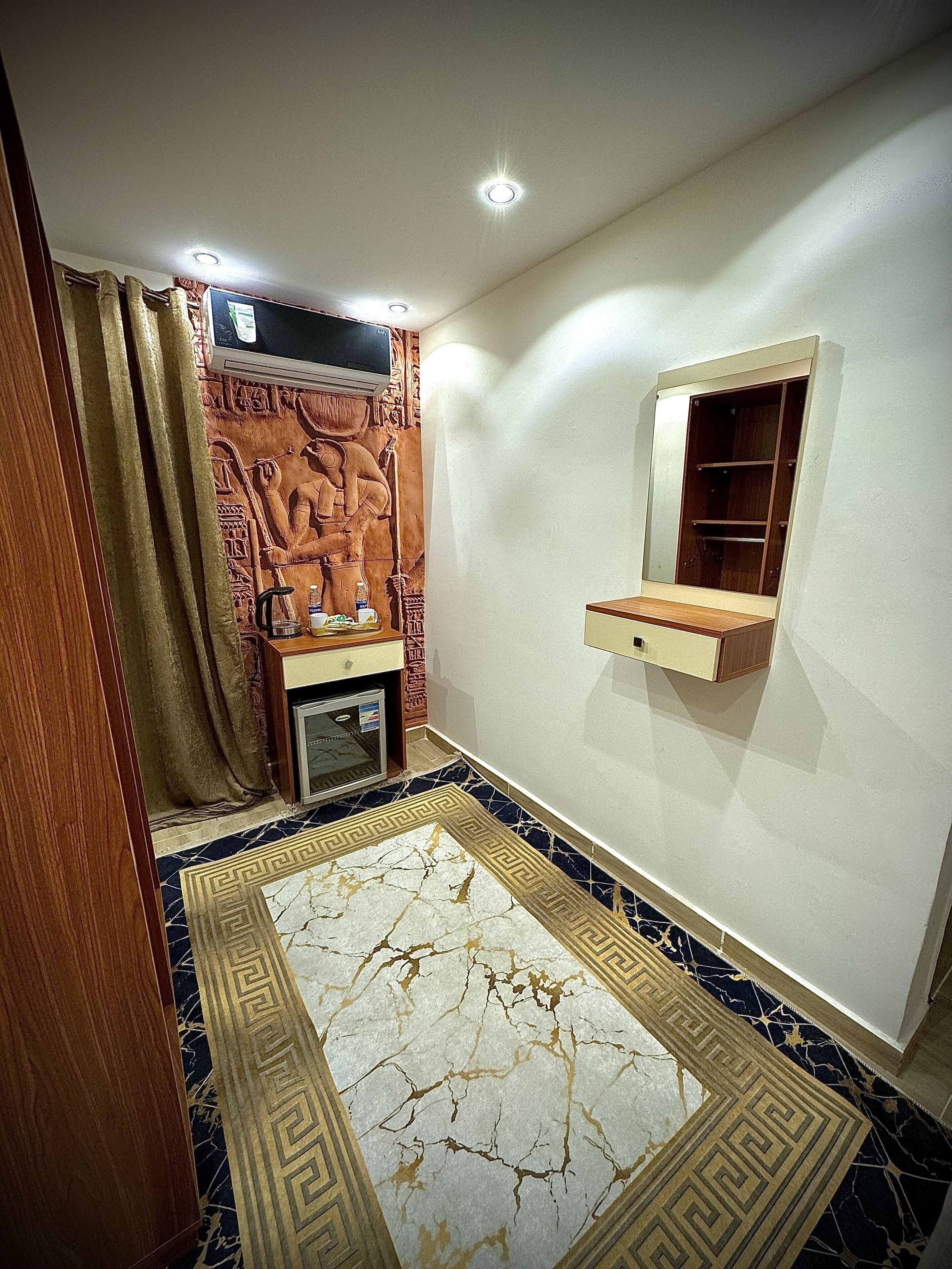 Une pièce dotée d’un sol à motifs de marbre, d’un meuble en bois, d’un petit lavabo et d’un panneau décoratif mural.