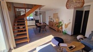 Un espacio habitable moderno con una escalera, comedor y sofá.