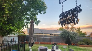 A patio with a table and chairs, a hanging pig decoration, and a fenced backyard. - Short term stay perfect for the business traveller
Pet friendly
 (Griffith)