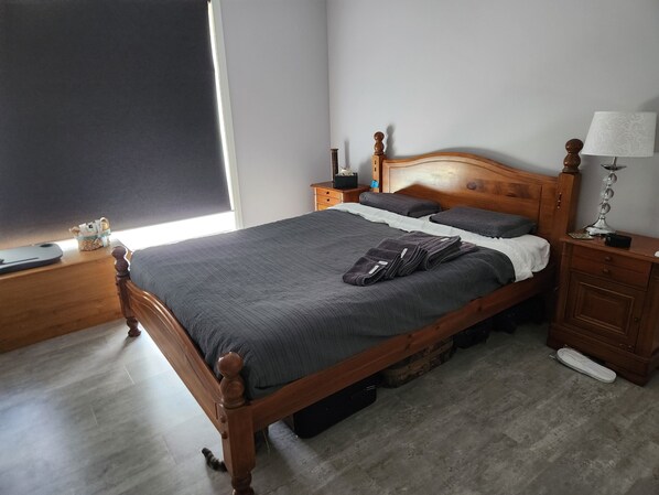 A neatly made bed with a wooden headboard, a bedside table with a lamp, and a small nightstand with a clock. - Short term stay perfect for the business traveller
Pet friendly
 (Griffith)