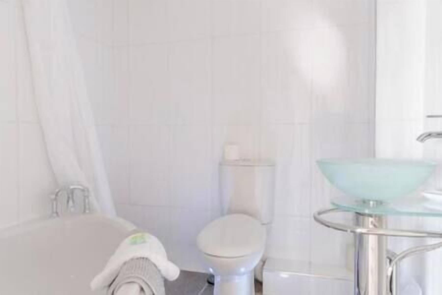 Un bagno con vasca, WC e lavandino in vetro.