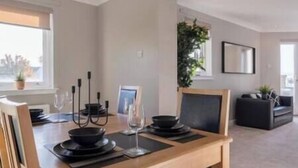 A dining area with a wooden table set for four, including plates, bowls, and a candelabra. - Penthouse at the Bay near Edinburgh (Dalgety Bay)