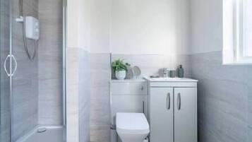 Un bagno moderno con doccia, servizi igienici e mobiletto.