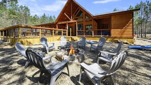 A log cabin with a deck, outdoor seating, and a fire pit.