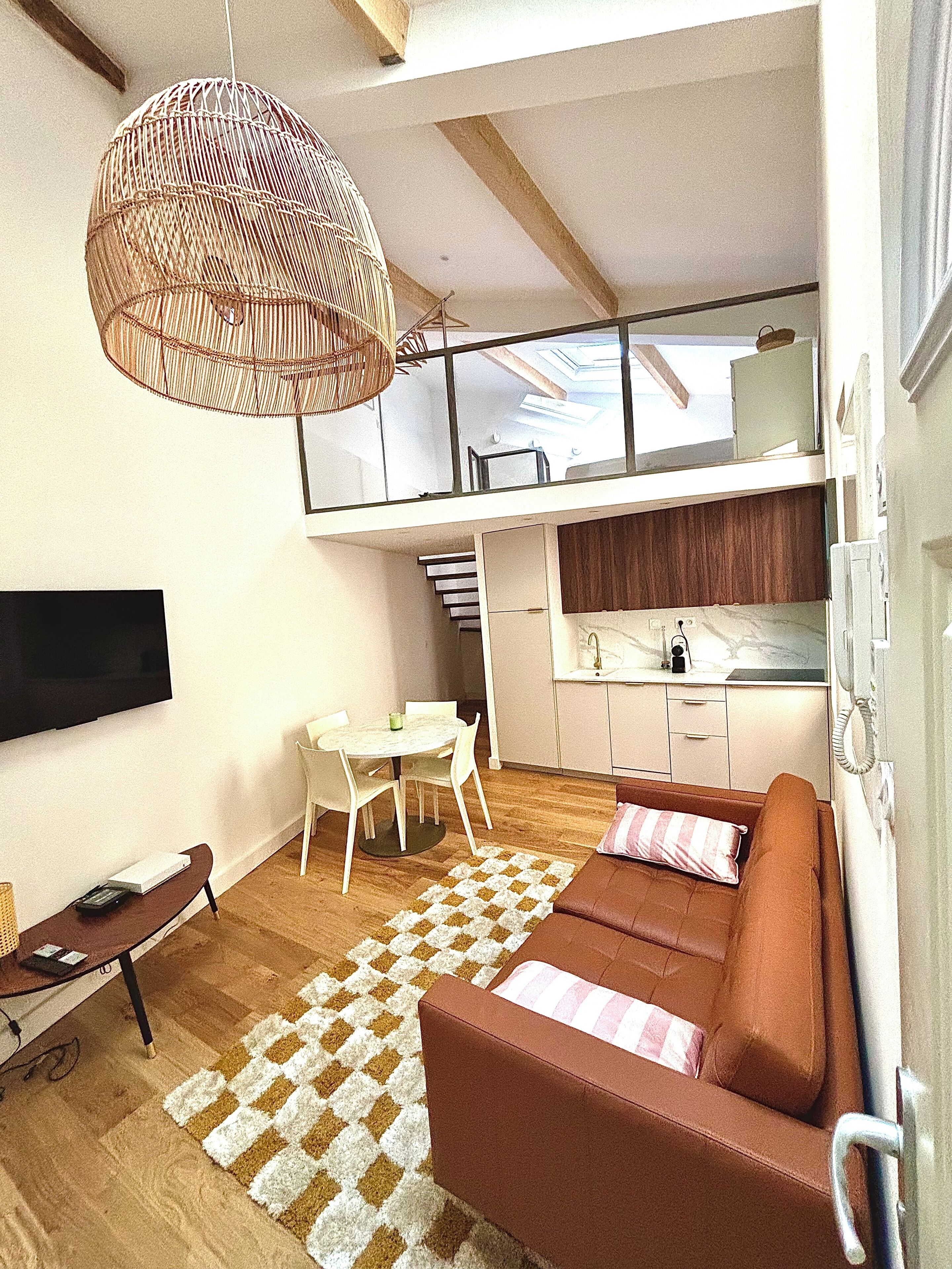 A modern living space with a sofa, a dining table, and a kitchen area.