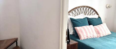A bedroom with a bed, a nightstand, and a wooden staircase.