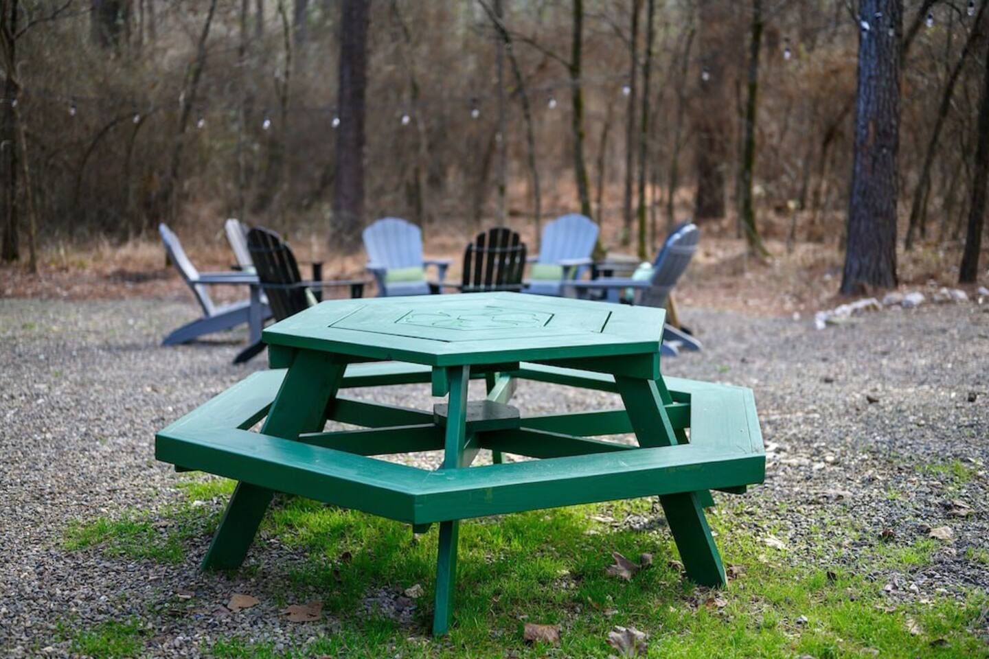 A green picnic table with a bench in a wooded area.