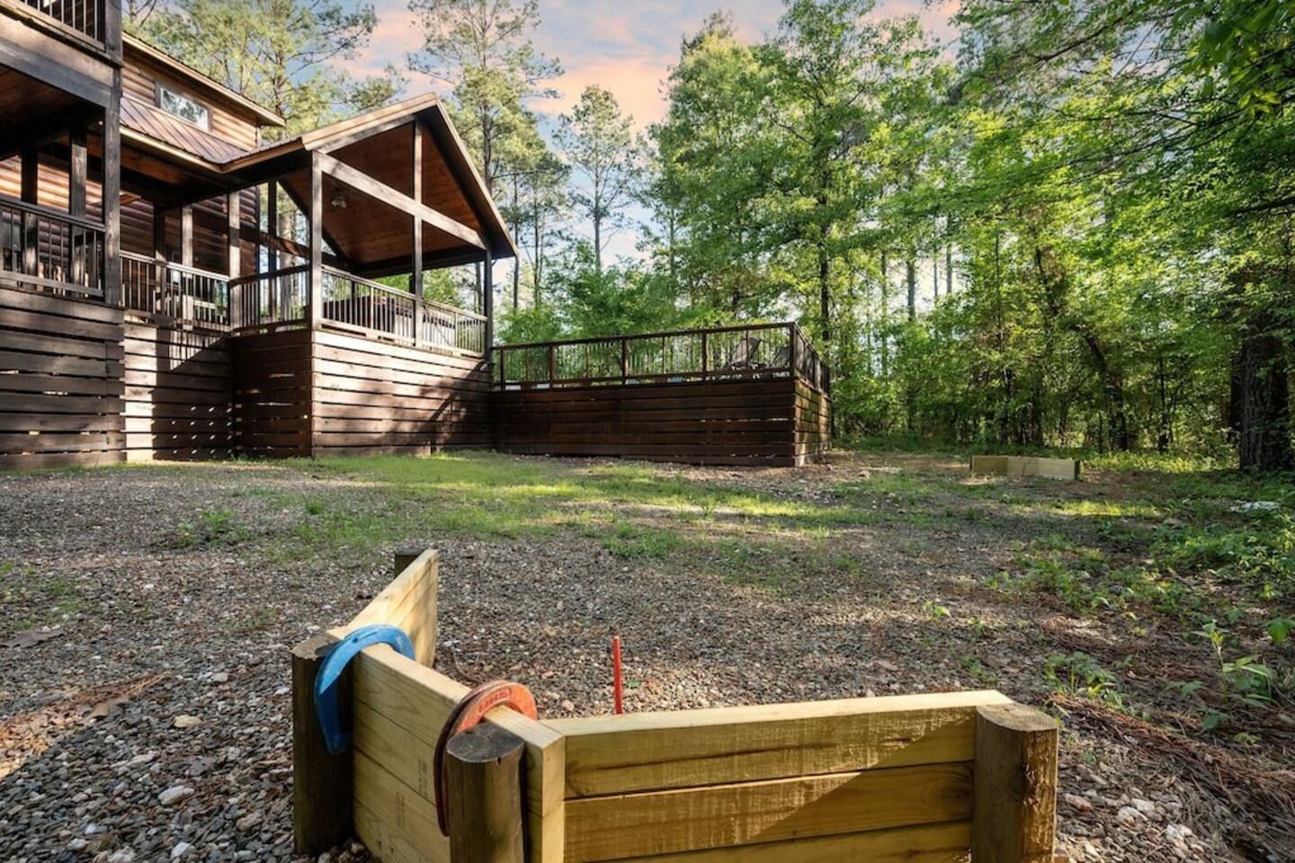 Une cabane en bois dotée d’une terrasse et d’un espace extérieur couvert, entourée d’arbres.