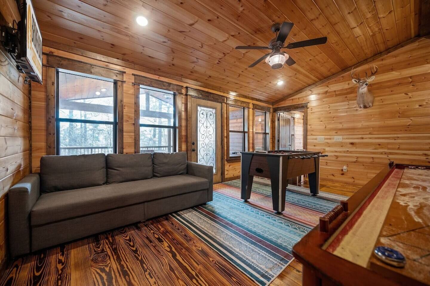 Une pièce confortable avec un canapé, une table de billard et un ventilateur de plafond.