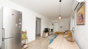 A modern kitchen with a stainless steel refrigerator, wooden dining table, and pendant lighting. - Modern Apartment Domina, With Balcony and Parking (Trogir)