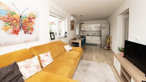 A modern living room with a sofa, a TV, and a kitchen in the background. - Modern Apartment Domina, With Balcony and Parking (Trogir)