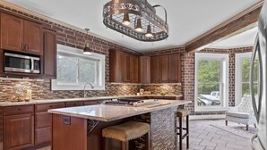 Una cocina con una isla central, armarios de madera, microondas integrado y un amplio ventanal con vistas al exterior.