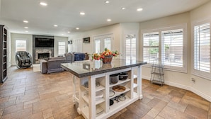 A spacious living area with a fireplace, a seating area, and a kitchen island with storage shelves. - Walk to State Farm Stadium! Poolside Desert Escape (Glendale)
