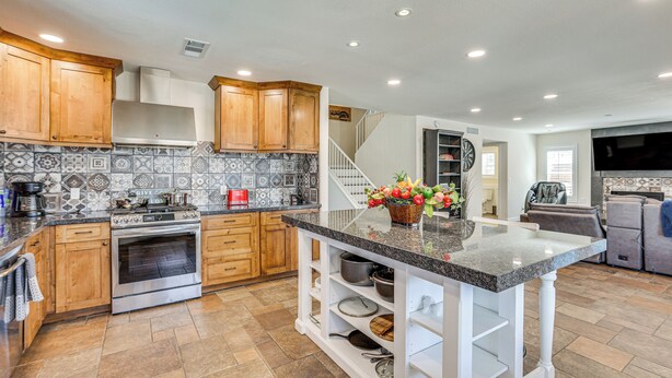 A modern kitchen with wooden cabinets, a built-in oven, and a granite countertop island. - Walk to State Farm Stadium! Poolside Desert Escape (Glendale)