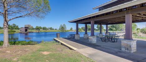 A covered outdoor area with picnic tables and a view of a lake.