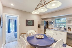 Uma cozinha moderna com armários brancos, uma mesa de jantar azul e uma geladeira de aço inoxidável.