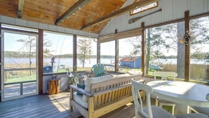 A wooden deck with a sofa, chairs, and a table, overlooking a lake with a dock and a small building in the background. - Dog-friendly Westover Cottage w/ River Access! (Westover)