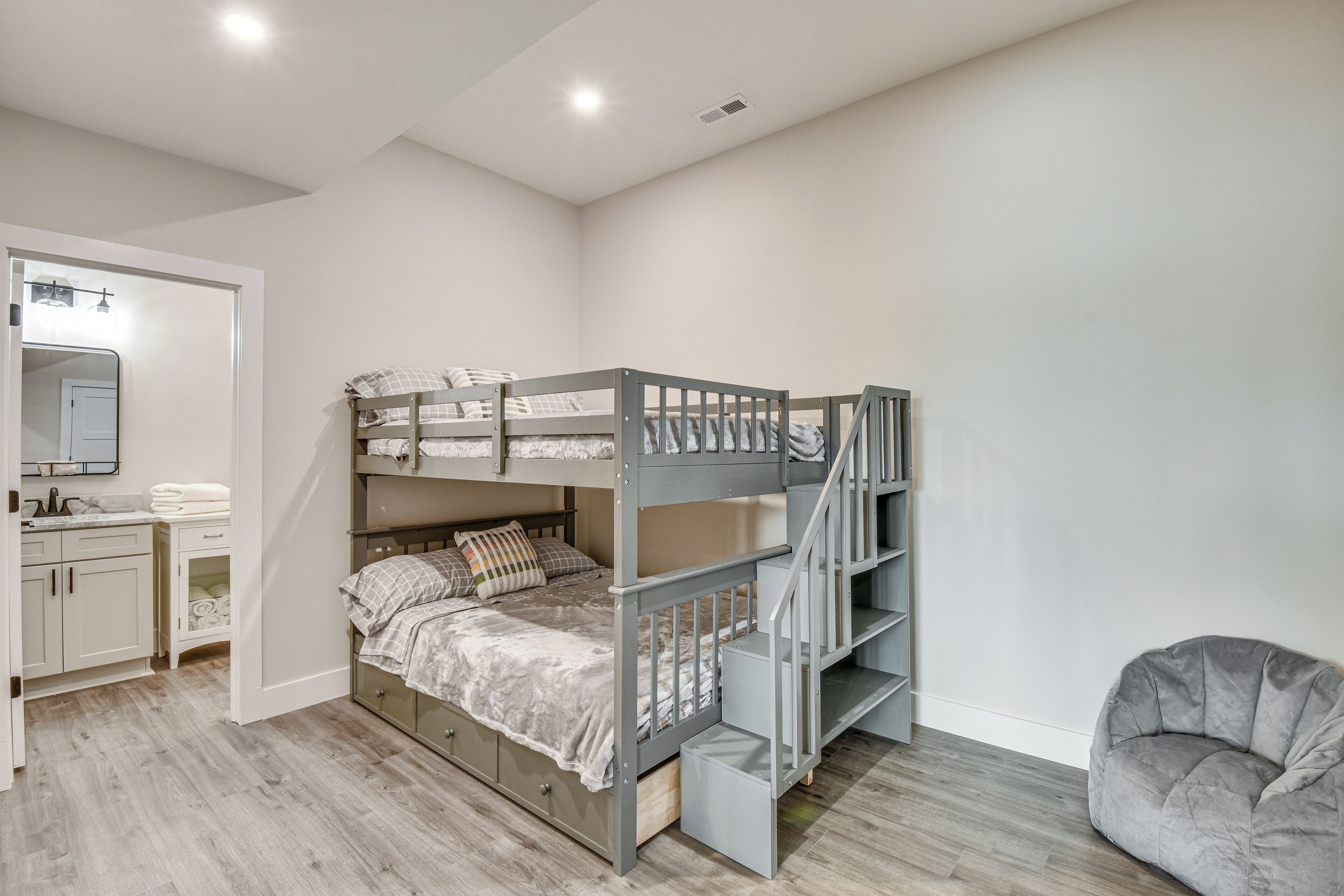A bunk bed with a desk and mirror, a grey bean bag chair, and a wooden floor.