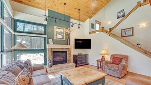 A spacious living room with a fireplace, comfortable seating, and a staircase.